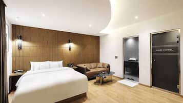 A modern hotel room with a large bed, a sofa, a small coffee table, and a wardrobe.
