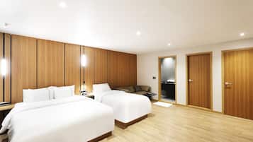 A hotel room with two beds, wooden paneling, a small seating area, and a bathroom visible through an open door.