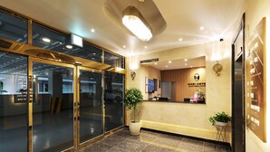 A hotel reception area with a reception desk, a large potted plant, and a wall-mounted TV. - marihotel (Seosan)