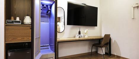 Une chambre d’hôtel équipée d’un mini-bar, d’une télévision à écran plat, d’un bureau en bois et d’une chaise.