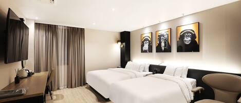 Habitación de hotel con dos camas, un escritorio, una silla y obras de arte en la pared.