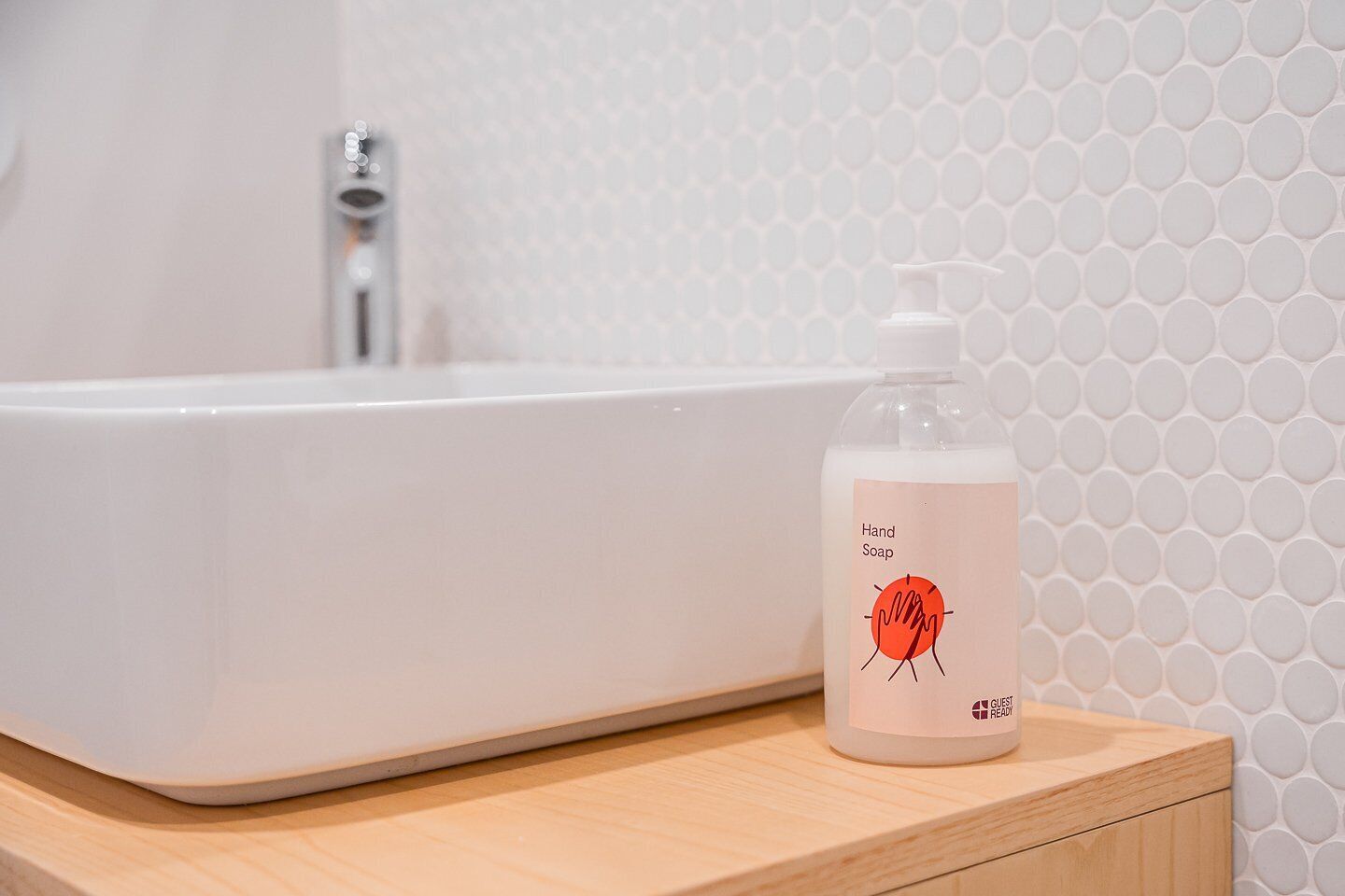 Ein Badezimmer mit einer weißen Badewanne und einer Handseifenflasche auf einer Holzauskład.