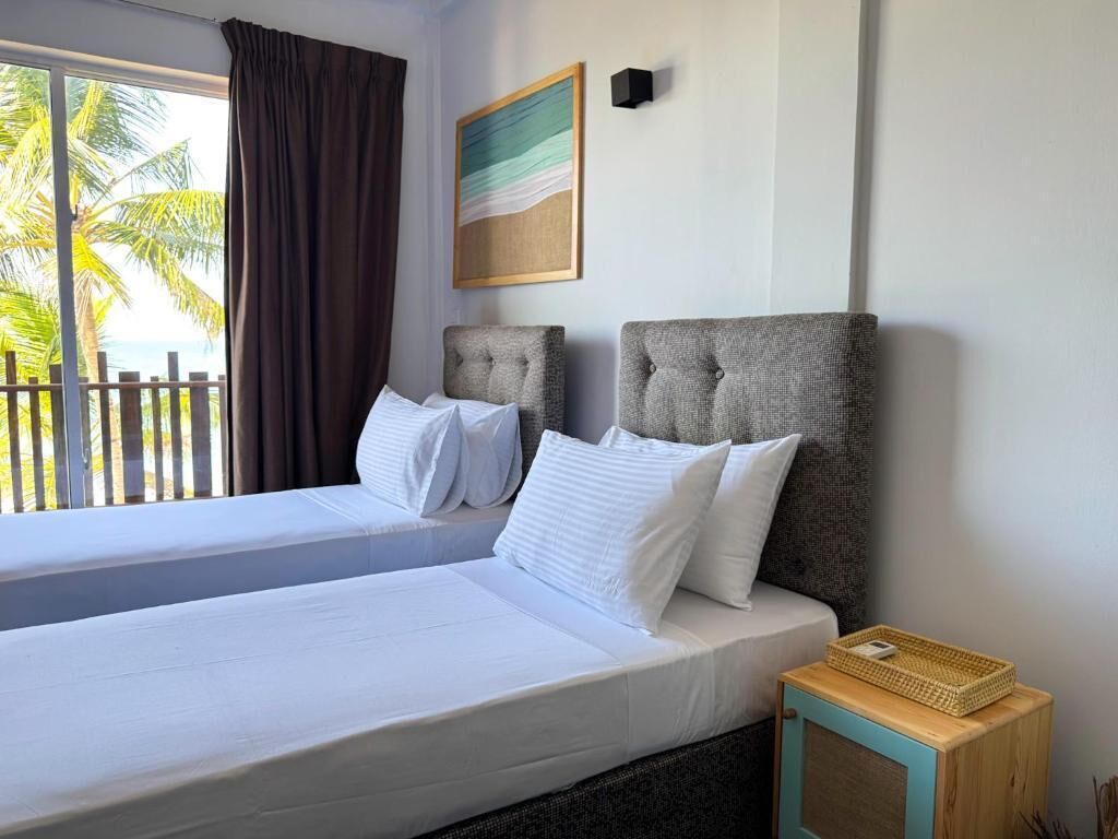 A double bed with white linens, a headboard, and a small wooden nightstand with a basket.