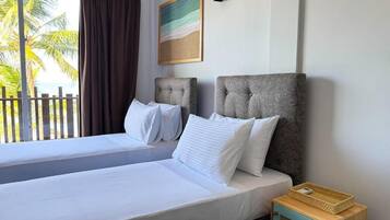 A double bed with white linens, a headboard, and a small wooden nightstand with a basket.