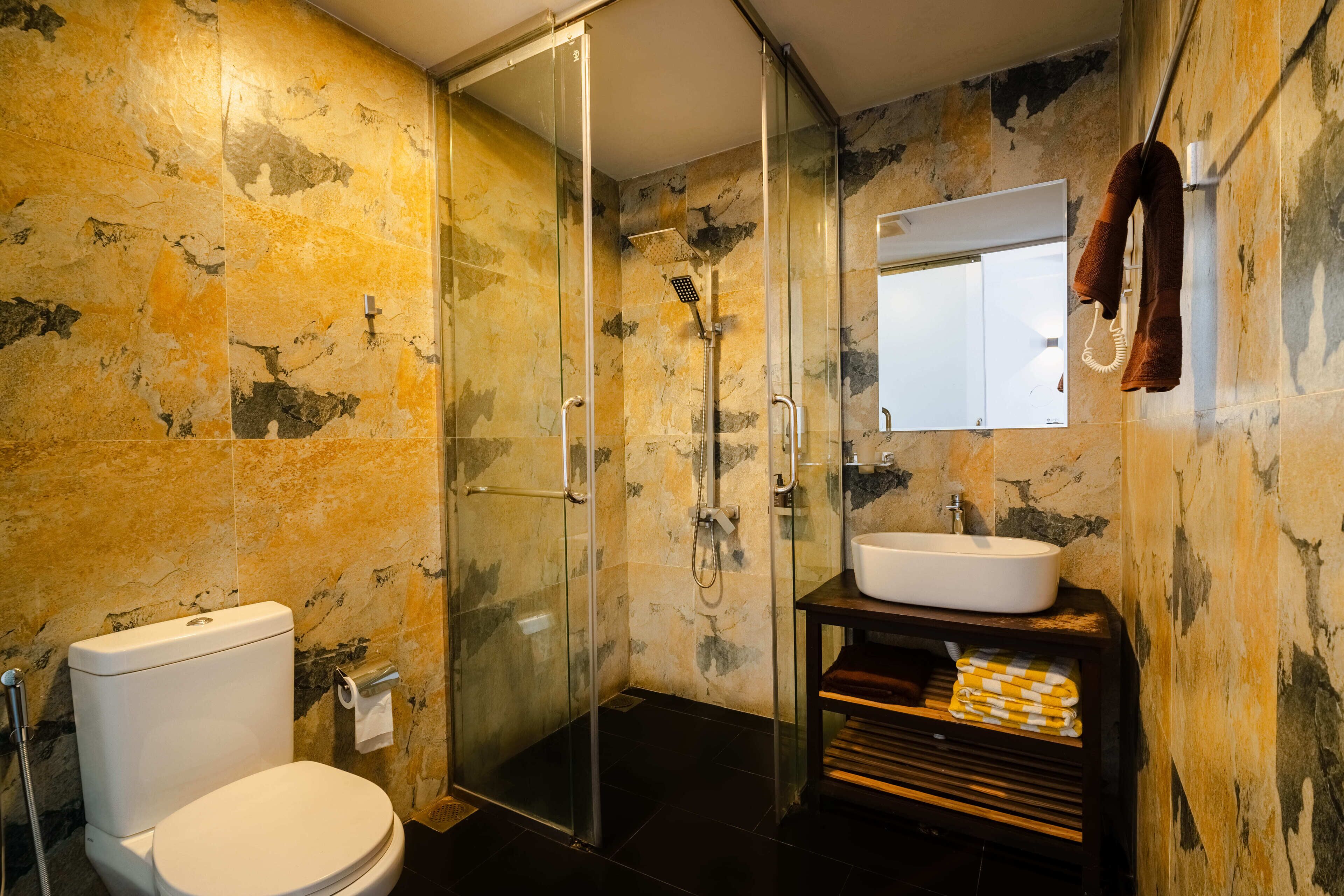 A bathroom with a glass-enclosed shower, a white toilet, and a sink with a mirror above it.
