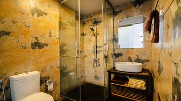 A bathroom with a glass-enclosed shower, a white toilet, and a sink with a mirror above it.