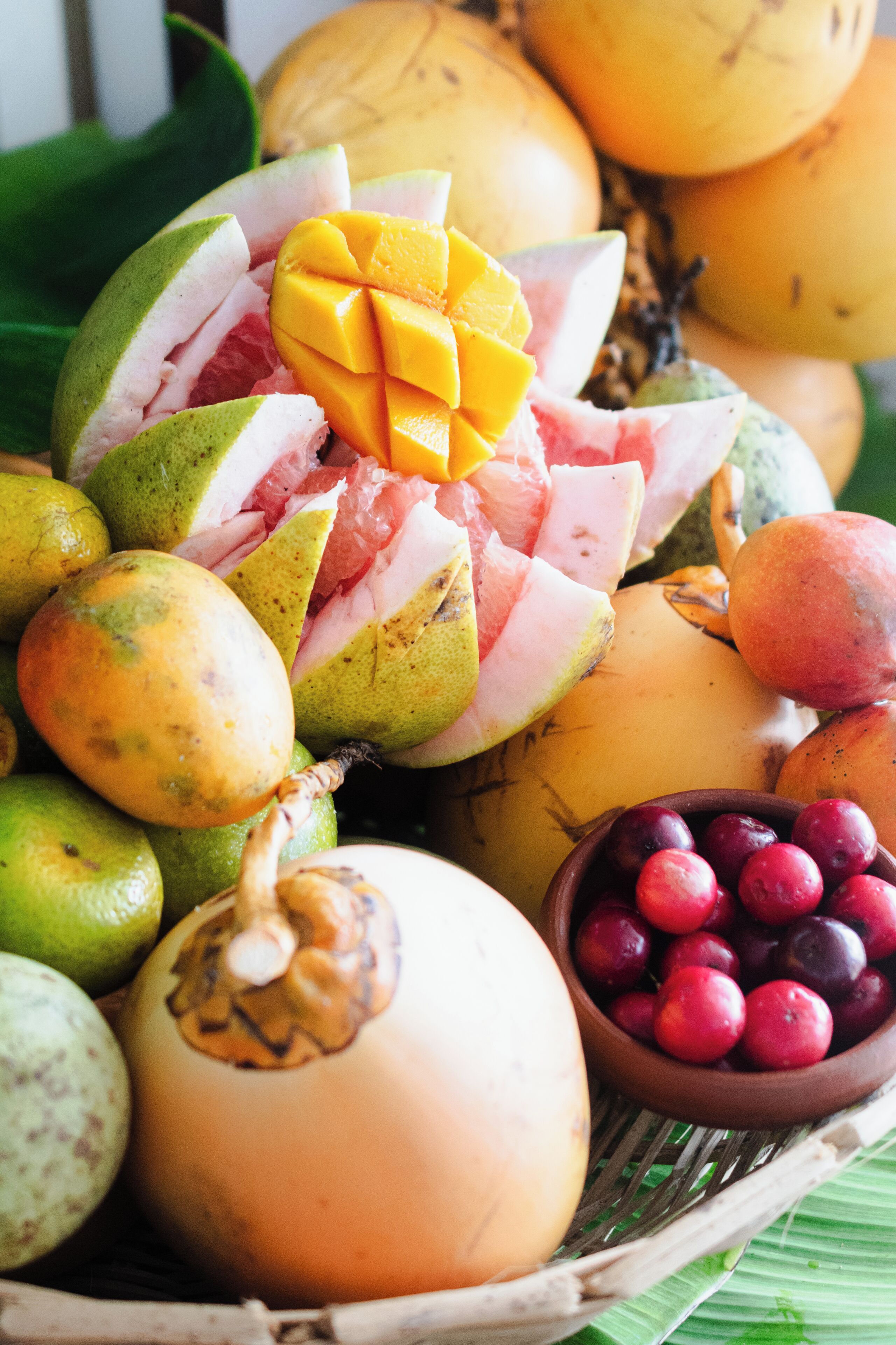 A variety of fruits including mangoes, bananas, and plums arranged in a basket.