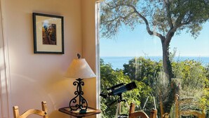 A dining area with a table, chairs, a lamp, and a telescope. - Lillie’s Oceanview RUSTIC Boho Surf Cottage 
Steps to the beach & fun! (Summerland)