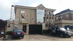 A building with a large garage door, a satellite dish, and a sign that reads "PER DOT". - Peridot Hotel and Suites (Lagos)