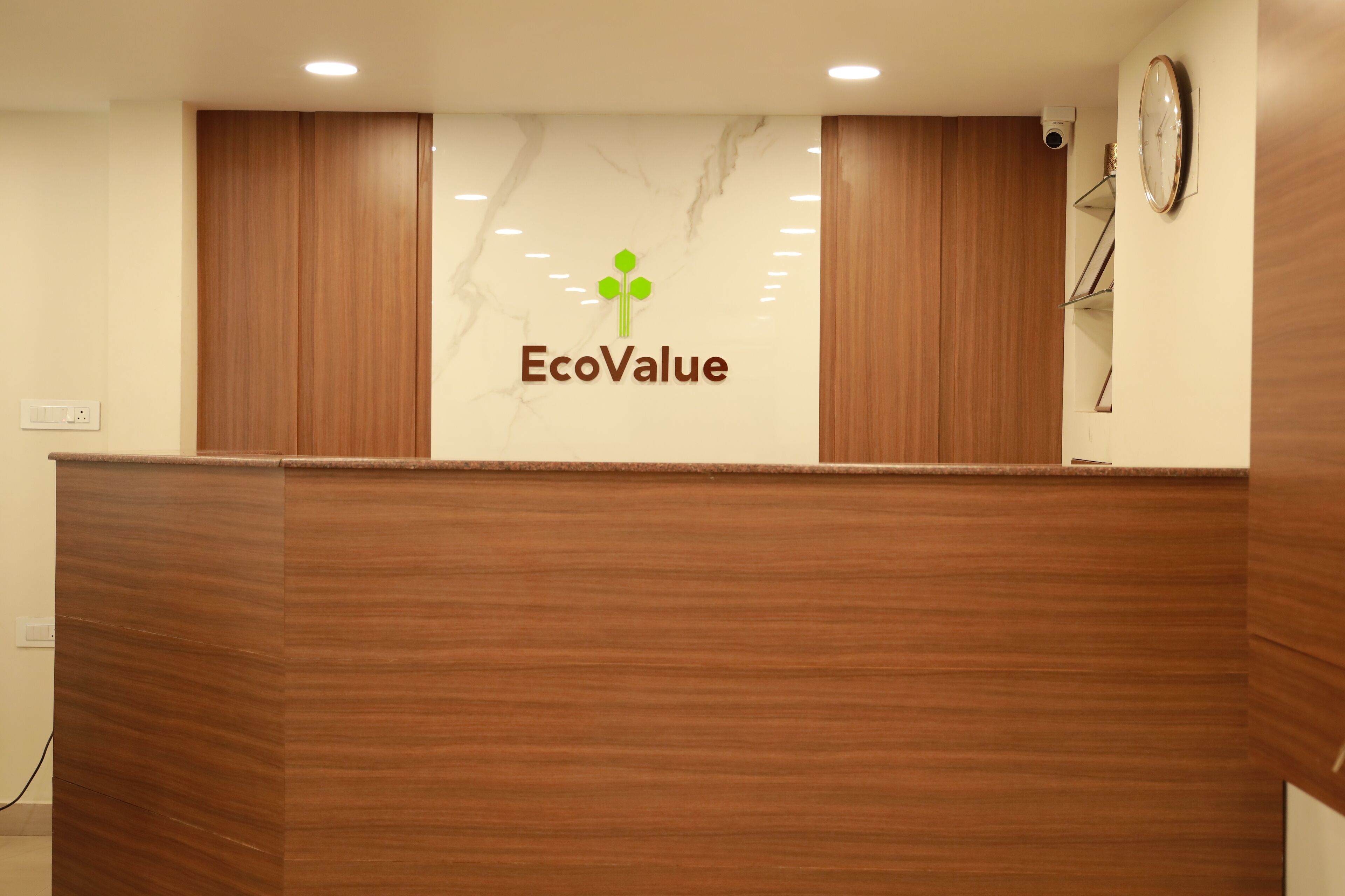 A reception desk with a logo that reads "EcoValue" and a clock on the wall.