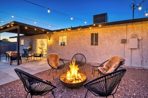 An outdoor patio with a fire pit, seating, and string lights. - Luxcation Lake Havasu Stay (Lake Havasu City)