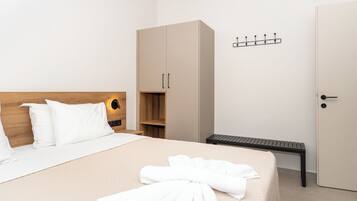 A hotel room with a bed, a wardrobe, a bench, and a coat rack.