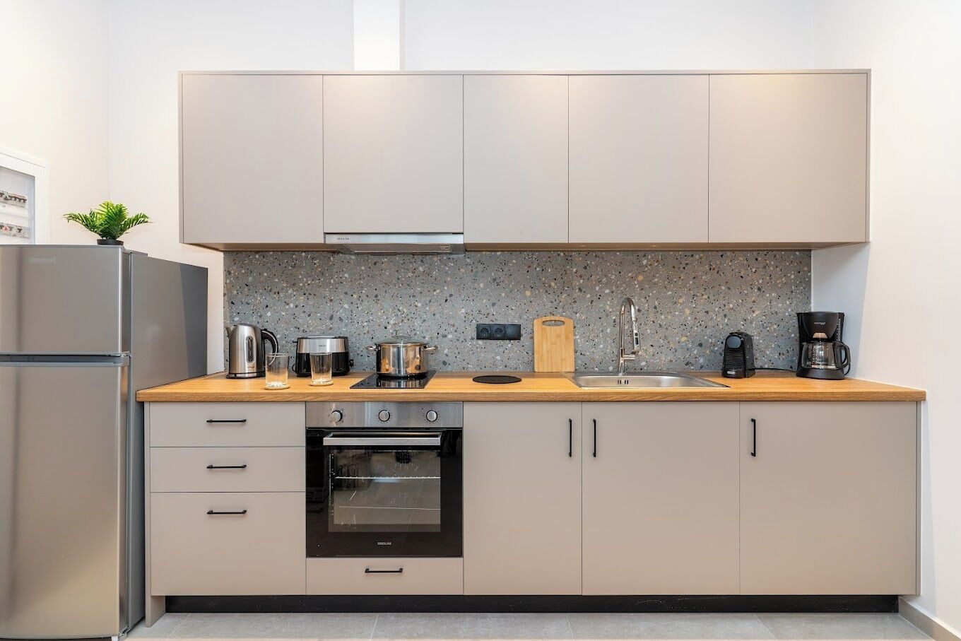 Eine moderne Küche mit Einbauofen, Kaffeemaschine und einer Spritzschutzwand aus Granit.