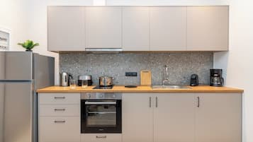 Una cocina moderna con horno empotrado, cafetera y salpicadero de encimera de granito.