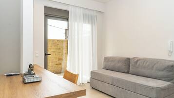 Una sala moderna con una mesa de comedor de madera, un sofá gris y vistas a una pared de piedra a través de un ventanal.