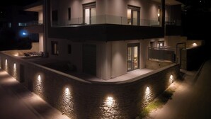 A modern two-story house with a balcony, stone exterior, and outdoor seating area. - Dreta Suites Chania (Chania)