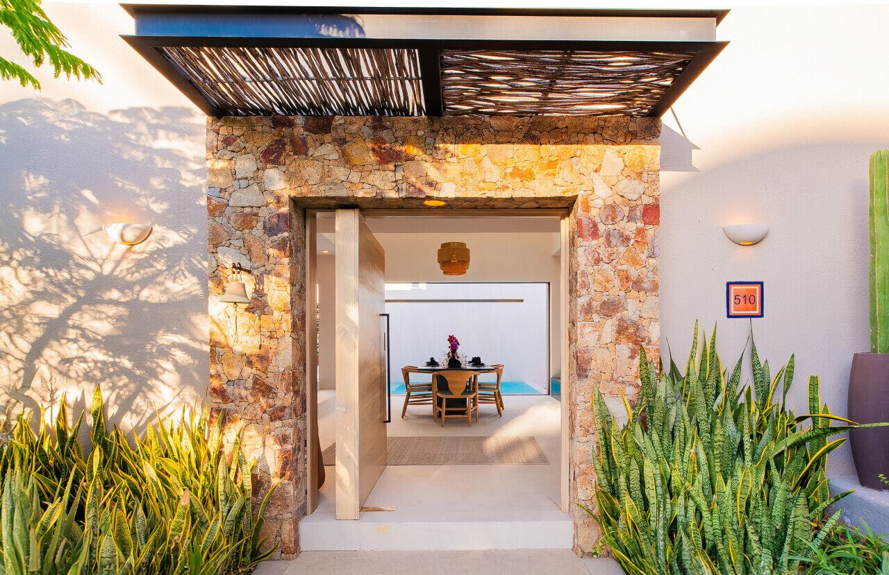 A stone archway leading to a dining area with a table and chairs.