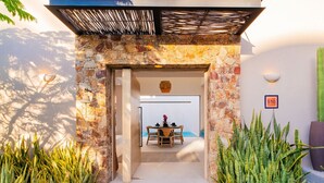 Un arco de piedra que da acceso a un comedor con una mesa y sillas.