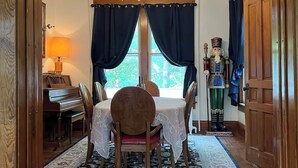 Un comedor con una mesa dispuesta para cuatro personas, una araña y vistas por la ventana.