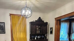Un salón con un sofá de cuero marrón, una mesa de centro de vidrio, un sillón gris y un aparador de madera oscura con objetos decorativos.