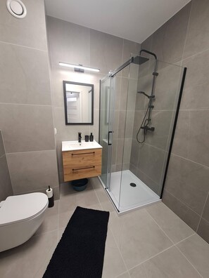Enjoy a refreshing shower in the sleek bathroom with a glass-enclosed shower, toilet, and vanity.