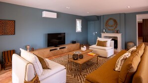 Ein modernes Wohnzimmer mit Fernseher, weißen Sofas, einem Couchtisch und einem Kamin.