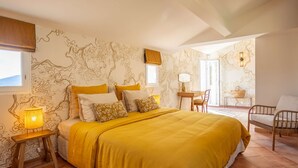 Ein Schlafzimmer mit einem großen Bett, einem Nachttisch, einem Sessel und einem kleinen Tisch mit einer Lampe.