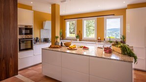 Eine moderne Küche mit einer großen Kochinsel, integrierten Geräten und viel natürlichem Licht durch große Fenster.