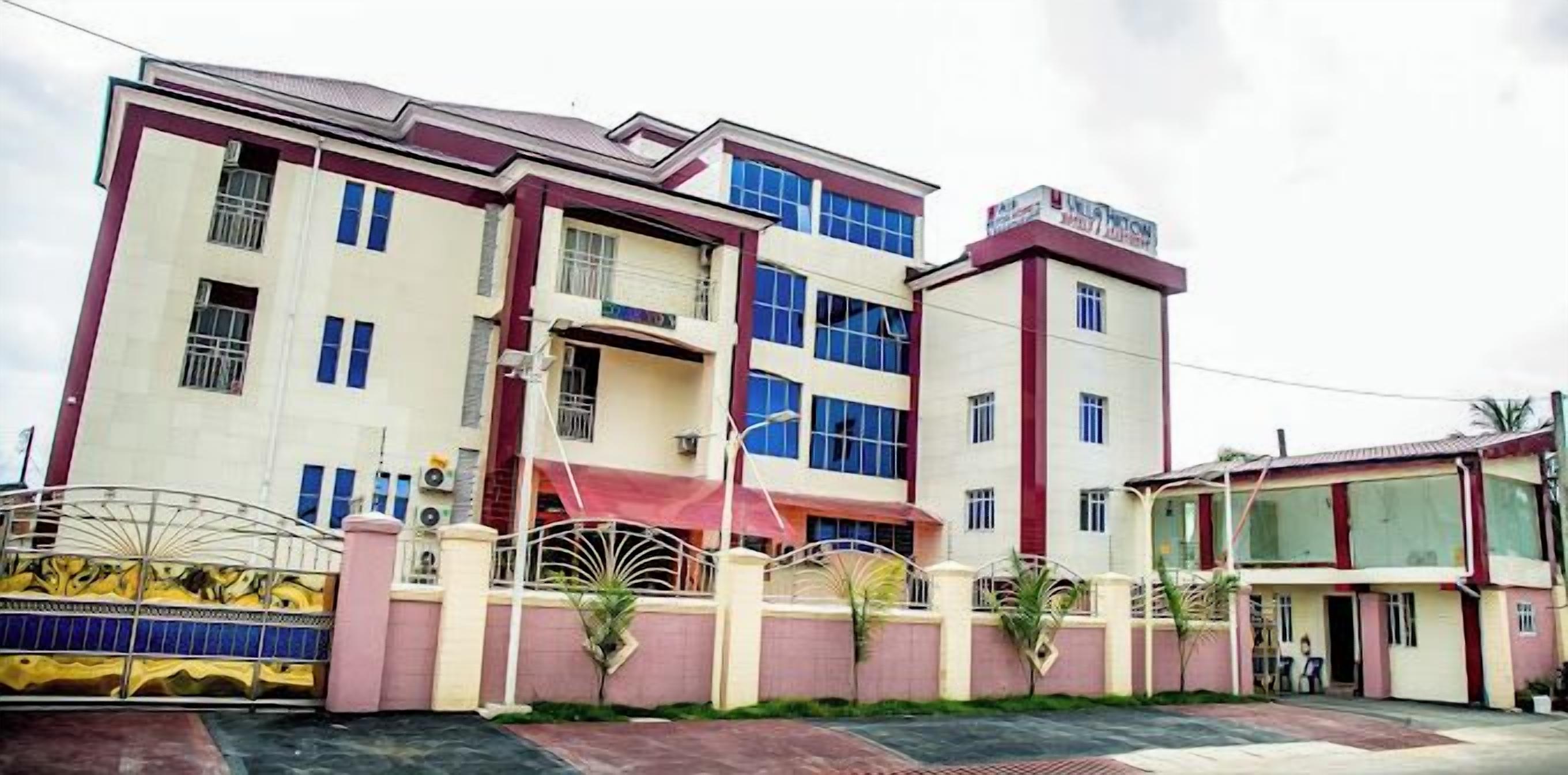 A multi-story building with a red and white facade, large windows, and a gated entrance.