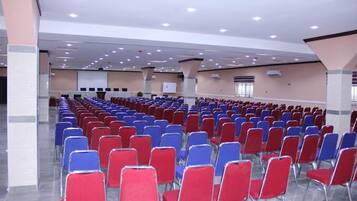 Un salón amplio con filas de sillas rojas y azules dispuestas para un evento.