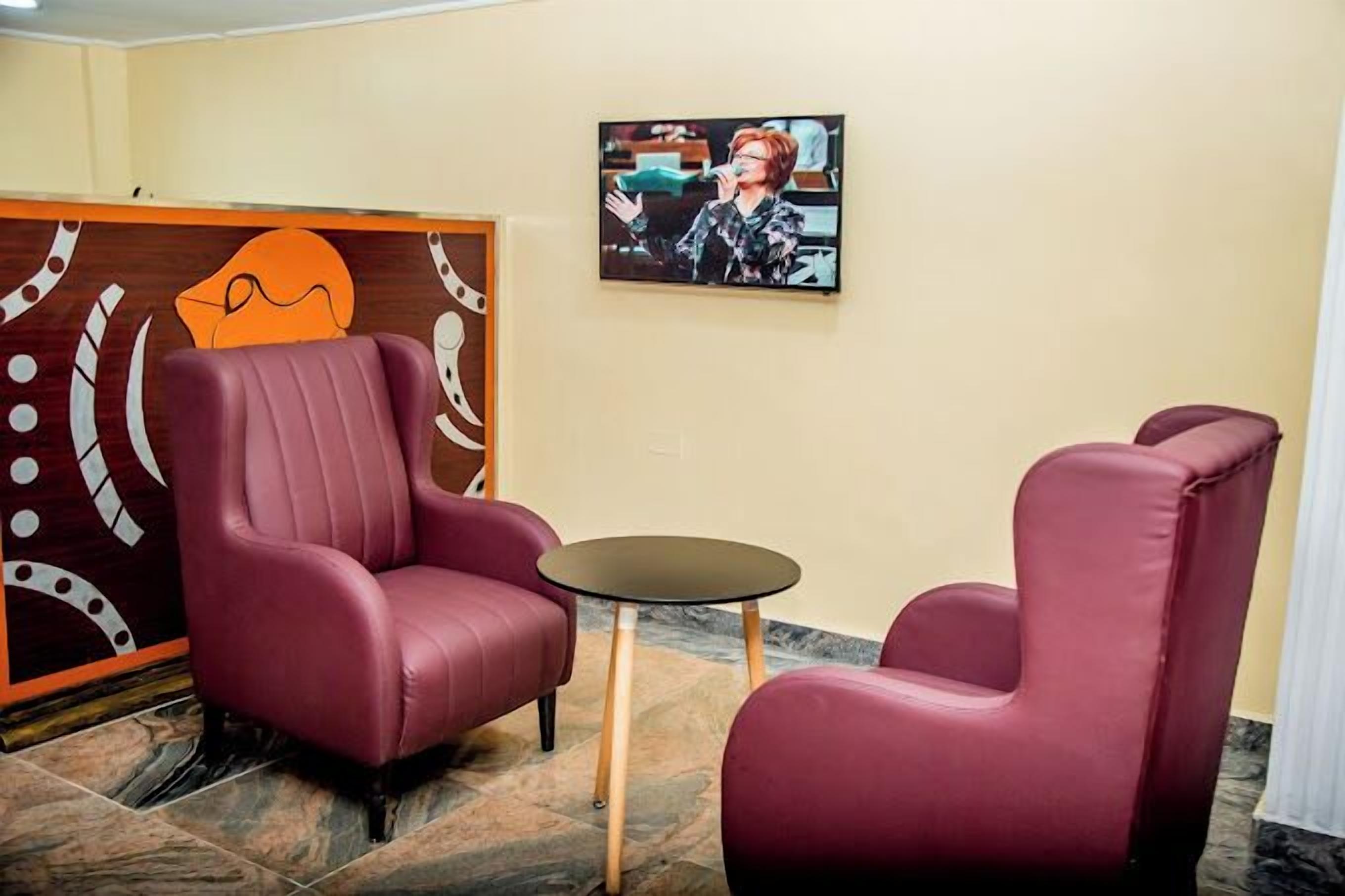 Ein Zimmer mit zwei großen, bequemen, roten Sesseln und einem kleinen runden Tisch.