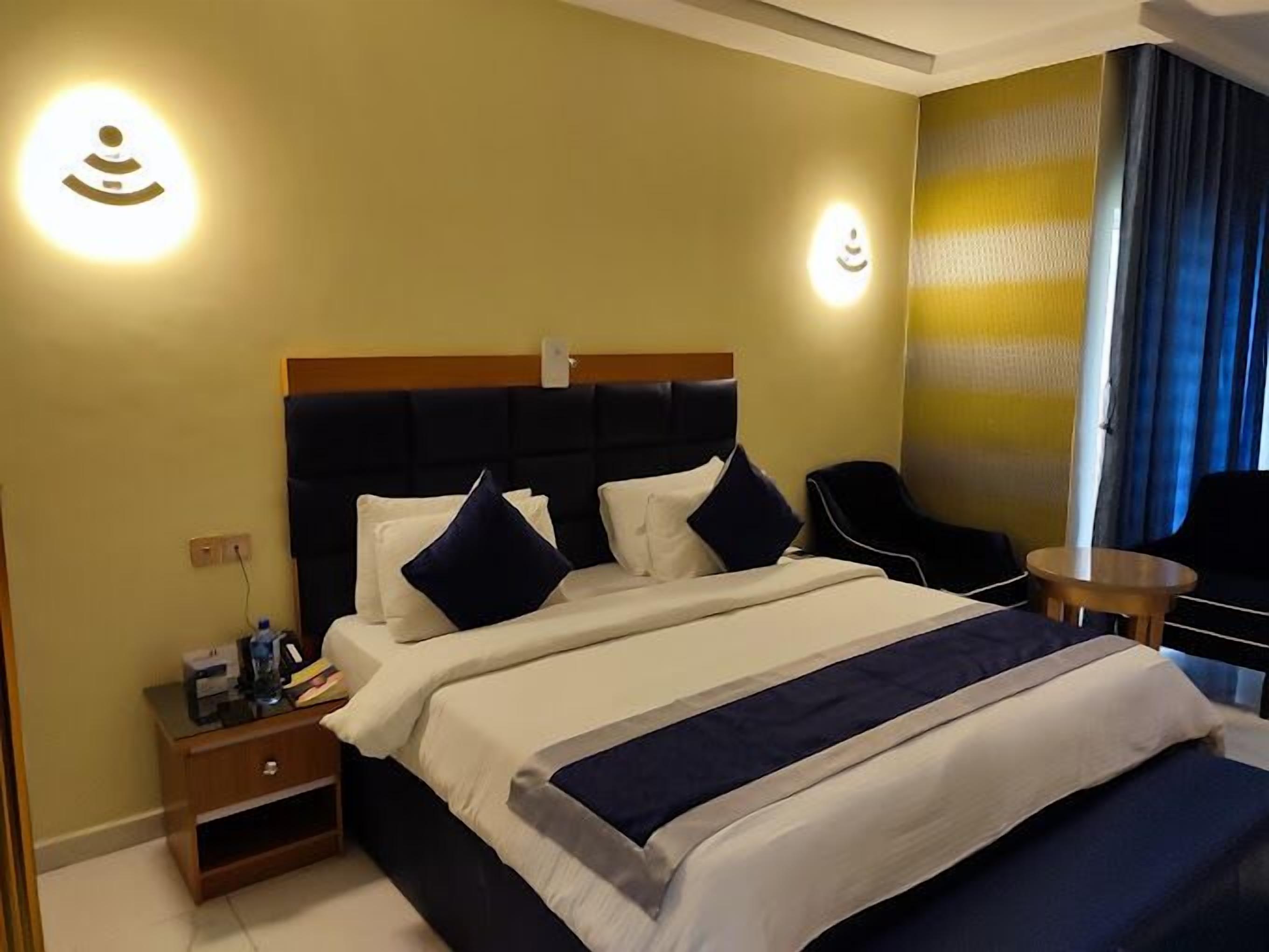 Een hotelkamer met een groot bed, een nachtkastje, een stoel en een tafeltje.