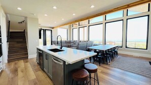 A modern kitchen with a large island, bar stools, and a dining area with a view. - Bear Lake getaway for the whole family! Sleeps 32! Beach access included!! (Garden City)