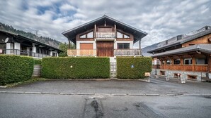 Ein Chalet mit Holzhülle, einem Balkon und einer Garage.