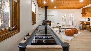 A modern kitchen with a long island, wooden ceiling, and a wood-burning stove. - Summit Sanctuary: Urban Elegance mins from Downtown (Flagstaff)