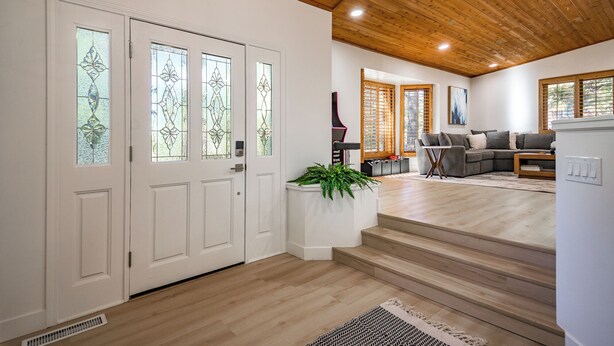 A modern living room with a wooden ceiling, a sectional sofa, and a staircase leading to another level. - Summit Sanctuary: Urban Elegance mins from Downtown (Flagstaff)
