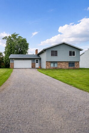 A two-story house with a garage, a gravel driveway, and a well-maintained lawn.