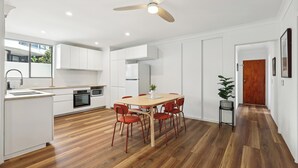 A modern kitchen with white cabinetry, a wooden dining table, and red chairs. - Coastal Hideaway on Palm Beach (Palm Beach)