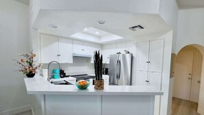 Una cocina moderna con armarios blancos, una isla central y un refrigerador empotrado.