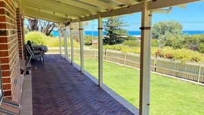 A covered patio with a brick floor, outdoor seating, and a view of the ocean. - Beautiful Ocean Views , Internet & Smart TV (Guilderton)