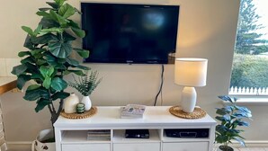 A white entertainment unit with a flat-screen TV, a lamp, and decorative items. - Beautiful Ocean Views , Internet & Smart TV (Guilderton)