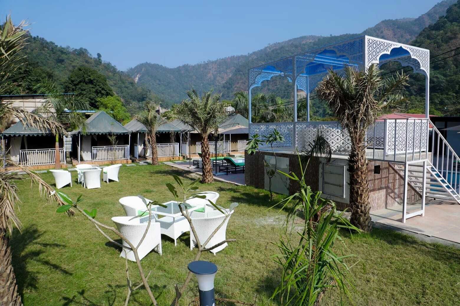 A resort with outdoor seating, a pool, and a view of the mountains.