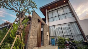 Un edificio moderno con fachada de piedra, ventanas amplias y una puerta de madera.