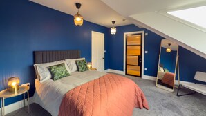 A bedroom with a bed, a nightstand, a mirror, and a door. - Egerton House Penrith -  a cottage that sleeps 8 guests in 4 bedrooms (Penrith)