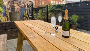 A wooden table with a bottle of champagne and two glasses on it. - Egerton House Penrith -  a cottage that sleeps 8 guests in 4 bedrooms (Penrith)