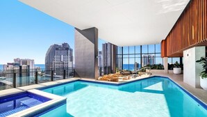 Ein Dachpool mit Blick auf die Stadt, Liegestühle und ein modernes architektonisches Design.
