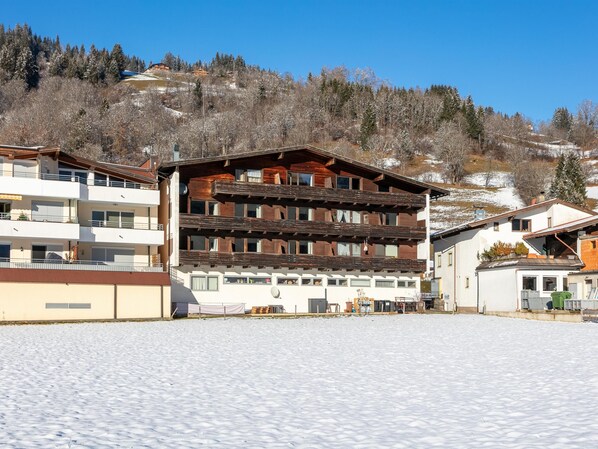 A multi-story building with balconies, a flat roof, and a snow-covered ground.