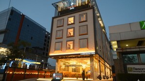 A hotel with a modern design, featuring a prominent entrance with steps leading up to the lobby, a balcony on the upper floor, and a sign indicating the hotel's name. - The Eco Satva Kota - Vegetarian with all Options (Kota)