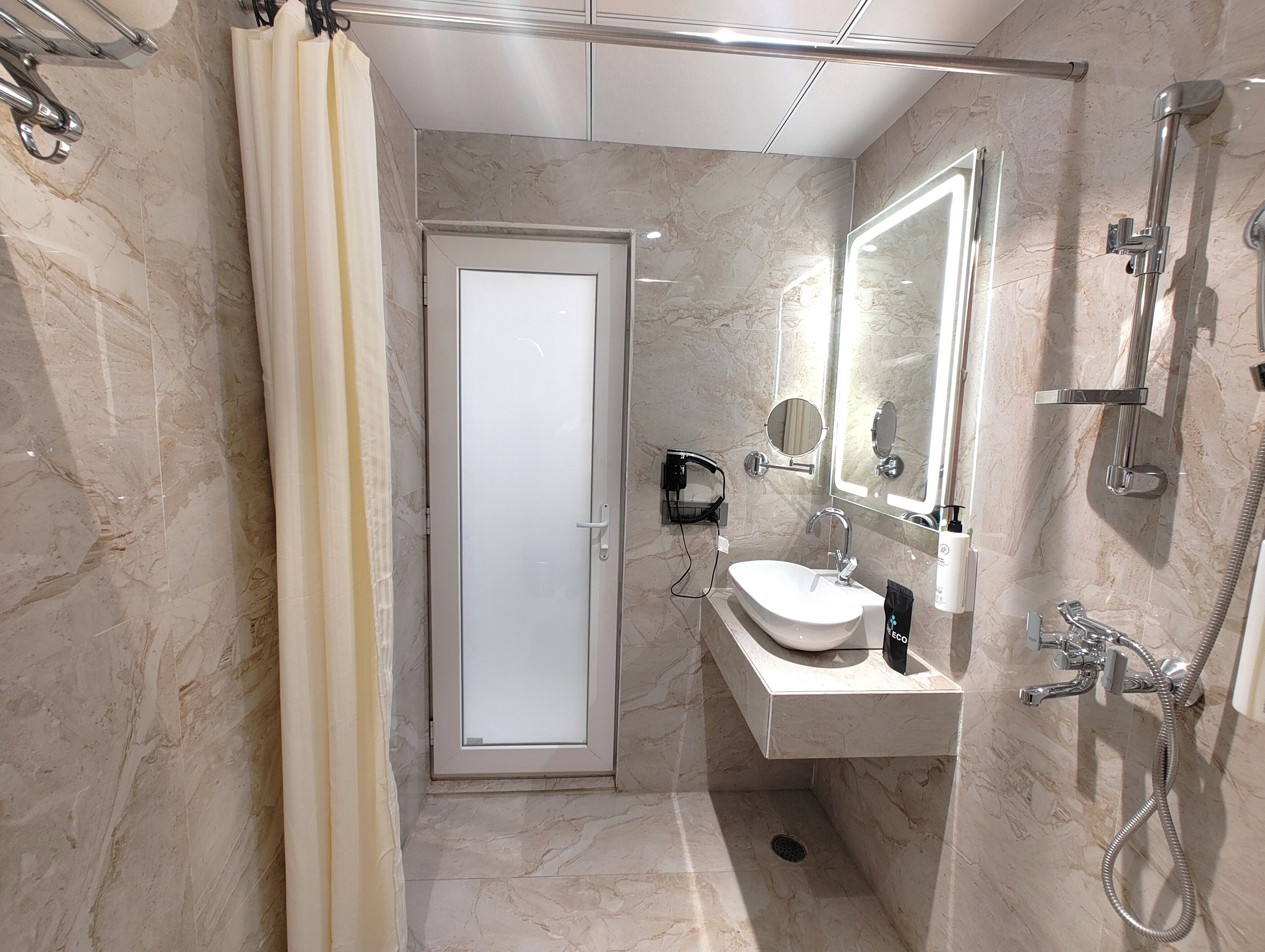 Un baño moderno con cabina de ducha de vidrio, un lavabo con espejo y un inodoro.