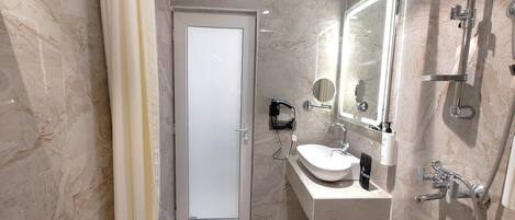 Un baño moderno con cabina de ducha de vidrio, un lavabo con espejo y un inodoro.
